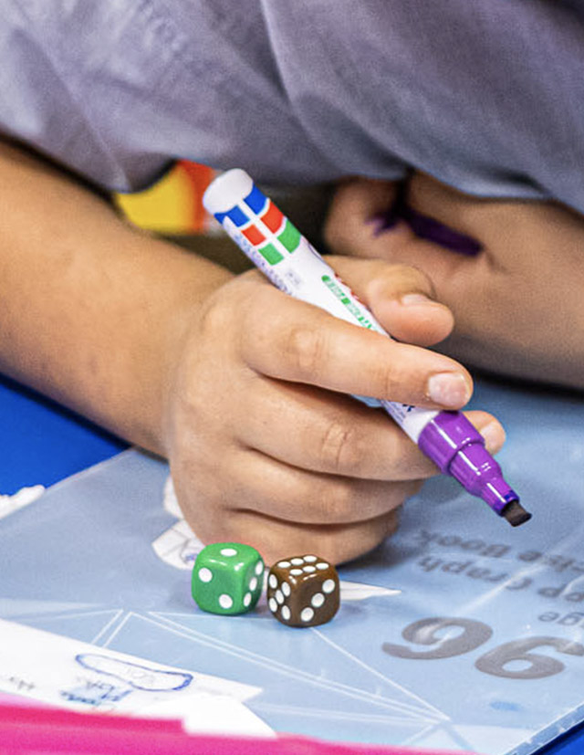 Sacred Heart Catholic Primary School Westmead student holding white board marker and dice