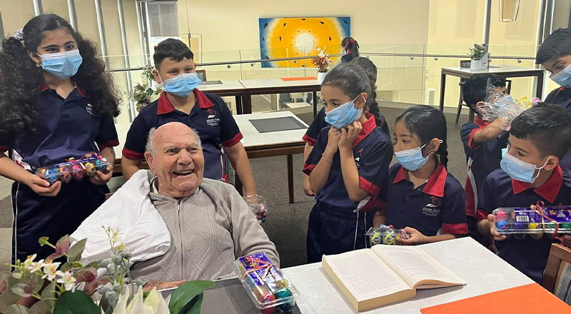 Sacred Heart Catholic Primary School Westmead students support an elderly man inside a local retirement home